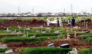 Petugas pemakaman mengangkat peti jenazah pasien Covid-19 untuk dikuburkan di TPU Rorotan, Jakarta, Kamis, 10 Februari 2022. (Foto: BeritaSatu Photo/Joanito De Saojoao)